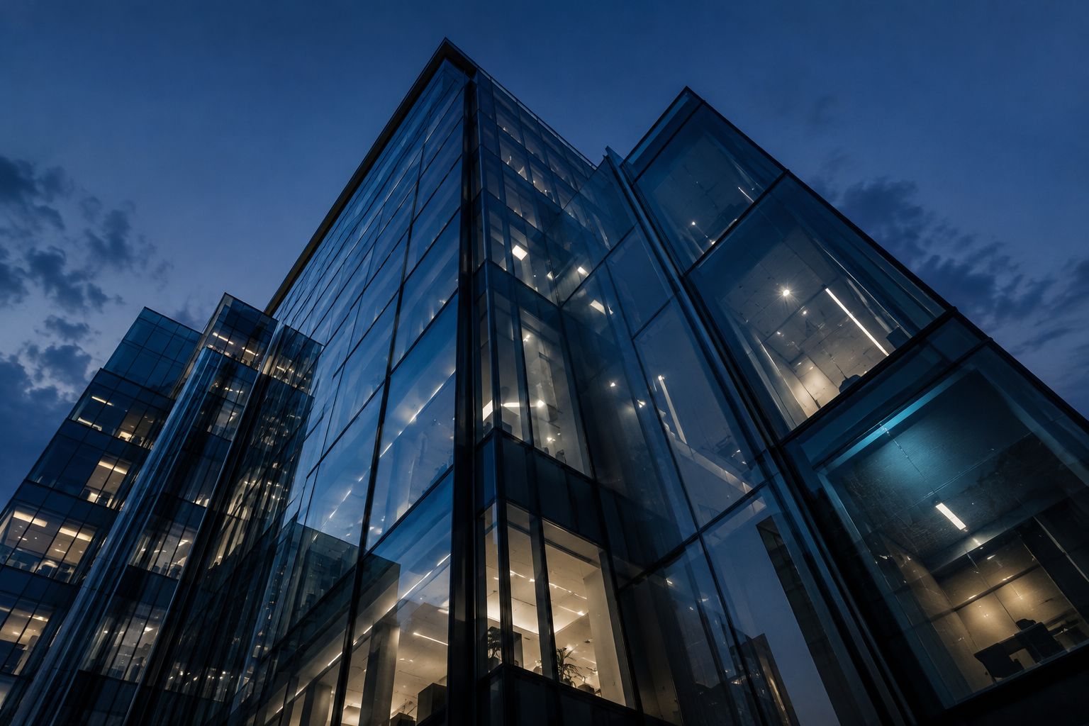 Looking up at a modern glass office building at dusk